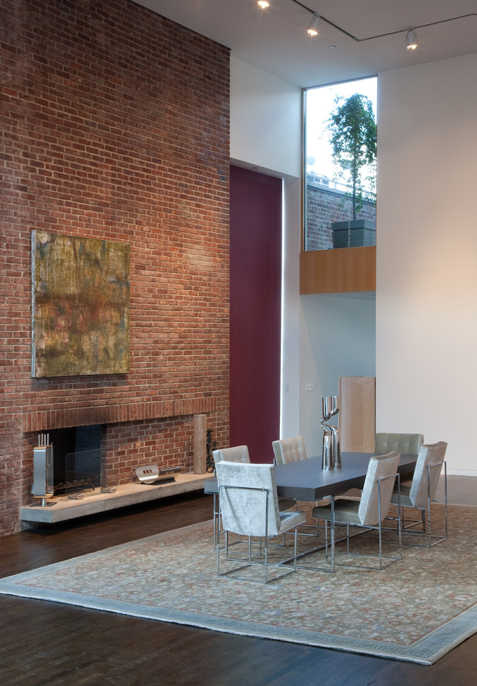 Photo of an expansive contemporary kitchen/dining combo in New York with white walls, dark hardwood floors, a standard fireplace and a brick fireplace surround.
