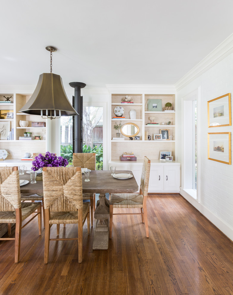 This is an example of a transitional dining room in Houston with white walls, medium hardwood floors and brown floor.