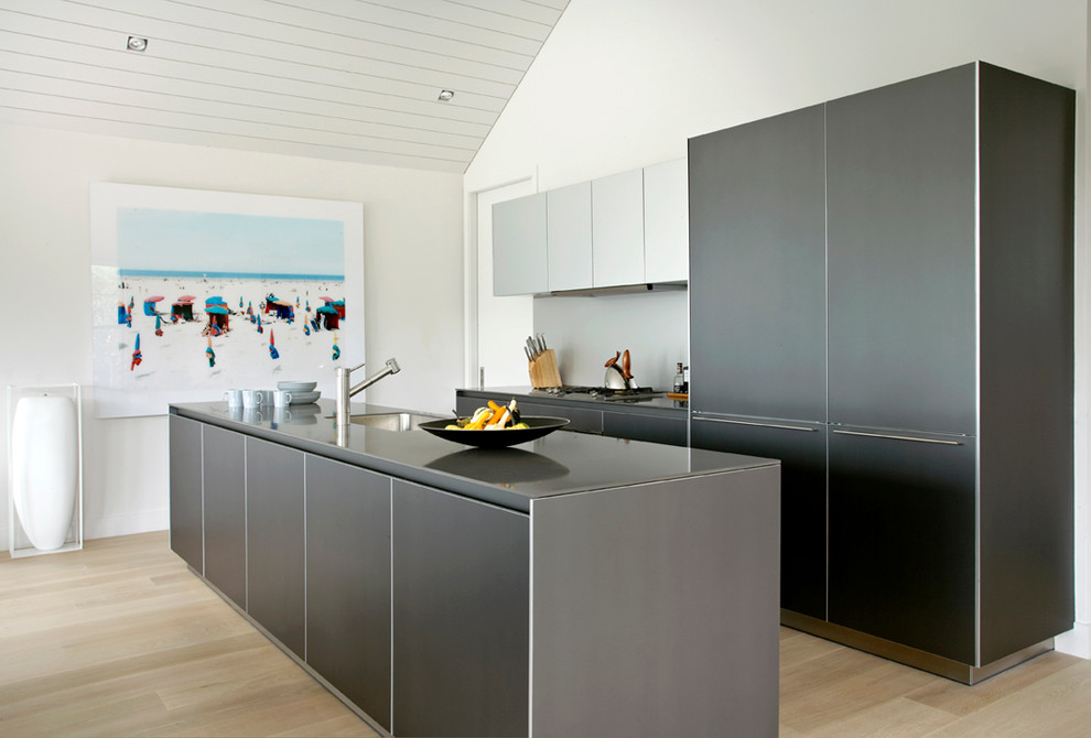 Contemporary galley open plan kitchen in New York with flat-panel cabinets, black cabinets, grey splashback and panelled appliances.