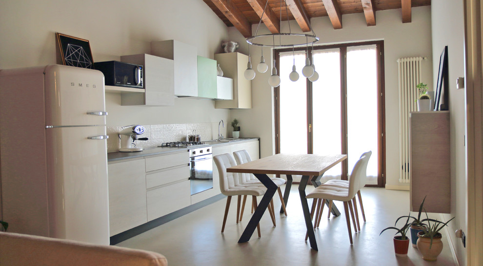 This is an example of a contemporary single-wall eat-in kitchen in Milan with a drop-in sink, flat-panel cabinets, light wood cabinets, quartzite benchtops, white splashback, subway tile splashback, stainless steel appliances, concrete floors and grey floor.