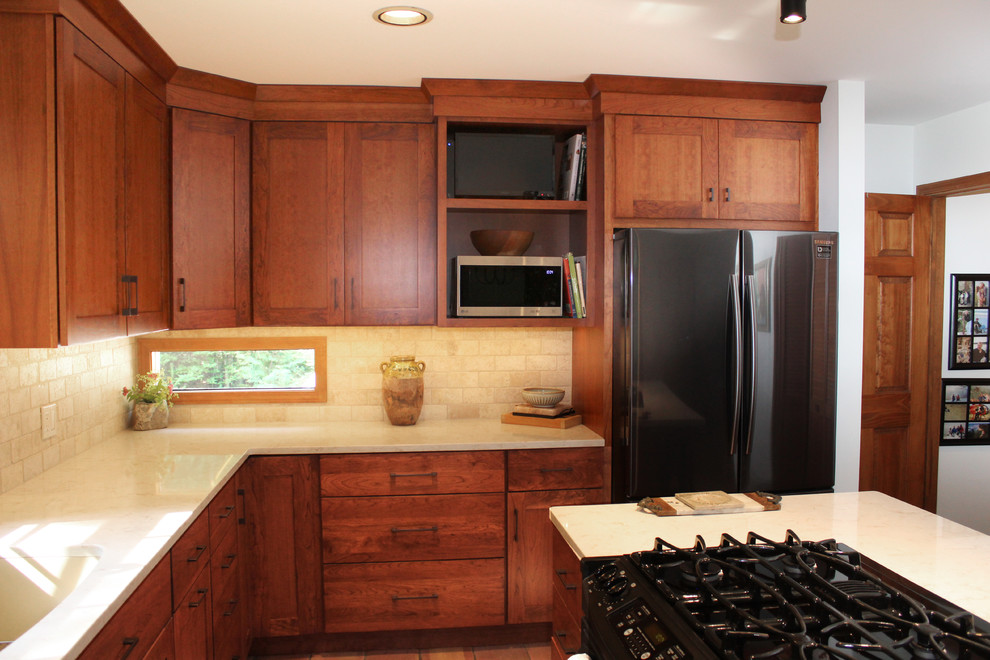 Example of a transitional l-shaped terra-cotta tile and red floor eat-in kitchen design with an undermount sink, shaker cabinets, medium tone wood cabinets, quartz countertops, beige backsplash, travertine backsplash, stainless steel appliances, an island and beige countertops