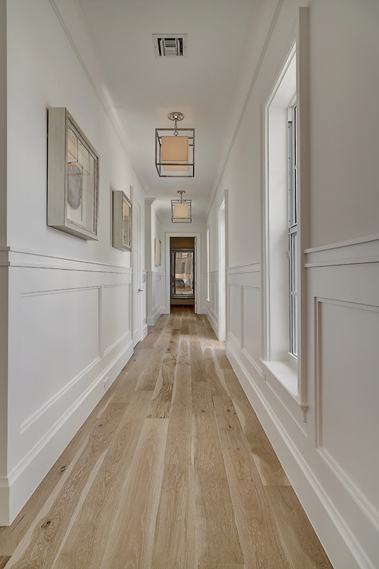 This is an example of a large beach style hallway in Miami with white walls, light hardwood floors and beige floor.
