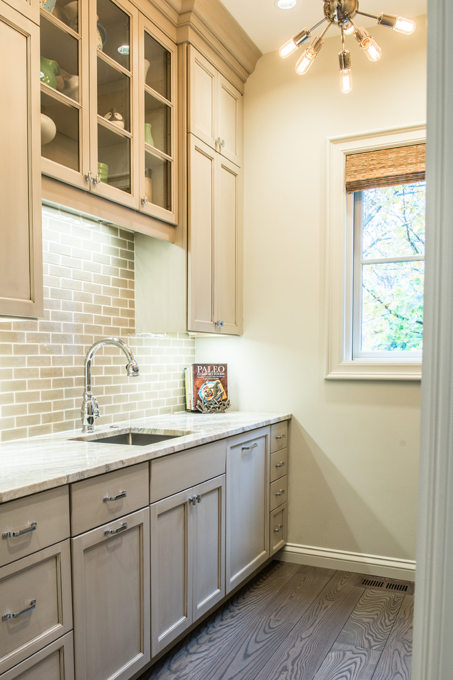 This is an example of a mid-sized country single-wall utility room in St Louis with an undermount sink, shaker cabinets, grey cabinets, marble benchtops, beige walls and dark hardwood floors.