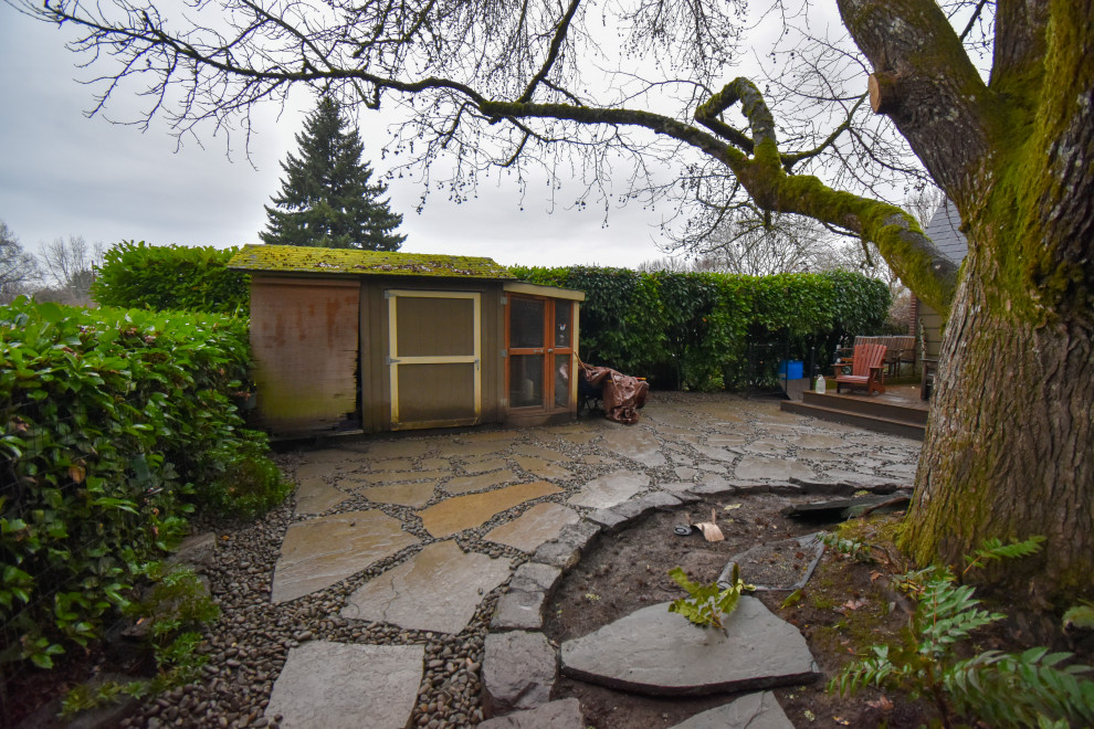 This is an example of a large backyard shaded garden in Portland with with rock feature and natural stone pavers.