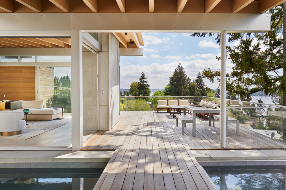 Design ideas for an expansive modern backyard deck in Seattle with a roof extension.