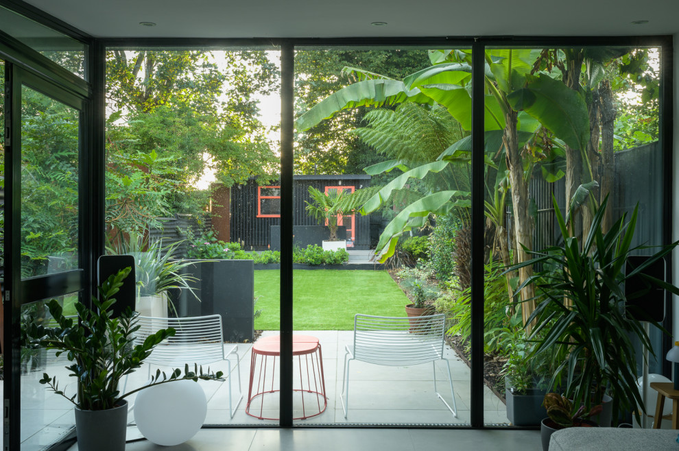 Idee per un giardino design esposto a mezz'ombra di medie dimensioni e dietro casa con pavimentazioni in pietra naturale e recinzione in metallo