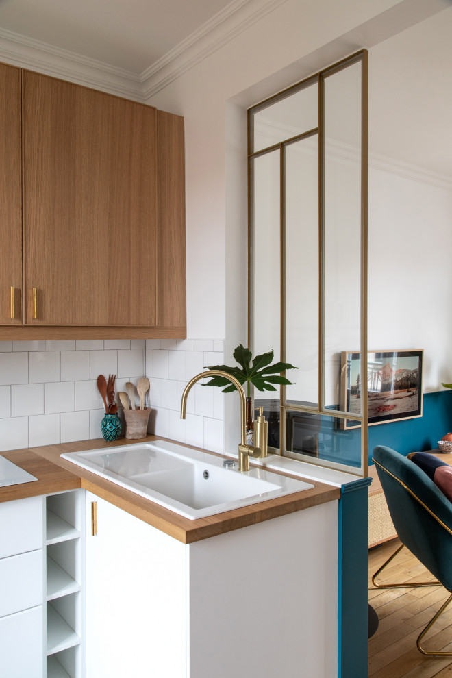 Inspiration for a mid-sized modern l-shaped open plan kitchen in Paris with a single-bowl sink, beaded inset cabinets, light wood cabinets, wood benchtops, white splashback, ceramic splashback, white appliances, cement tiles, no island, blue floor and beige benchtop.