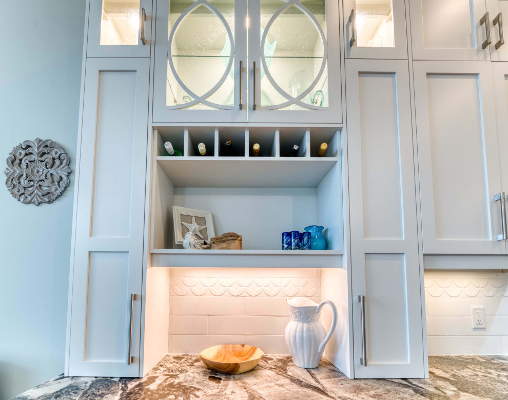Eat-in kitchen - large transitional l-shaped light wood floor and brown floor eat-in kitchen idea with a farmhouse sink, shaker cabinets, white cabinets, granite countertops, ceramic backsplash, stainless steel appliances and an island