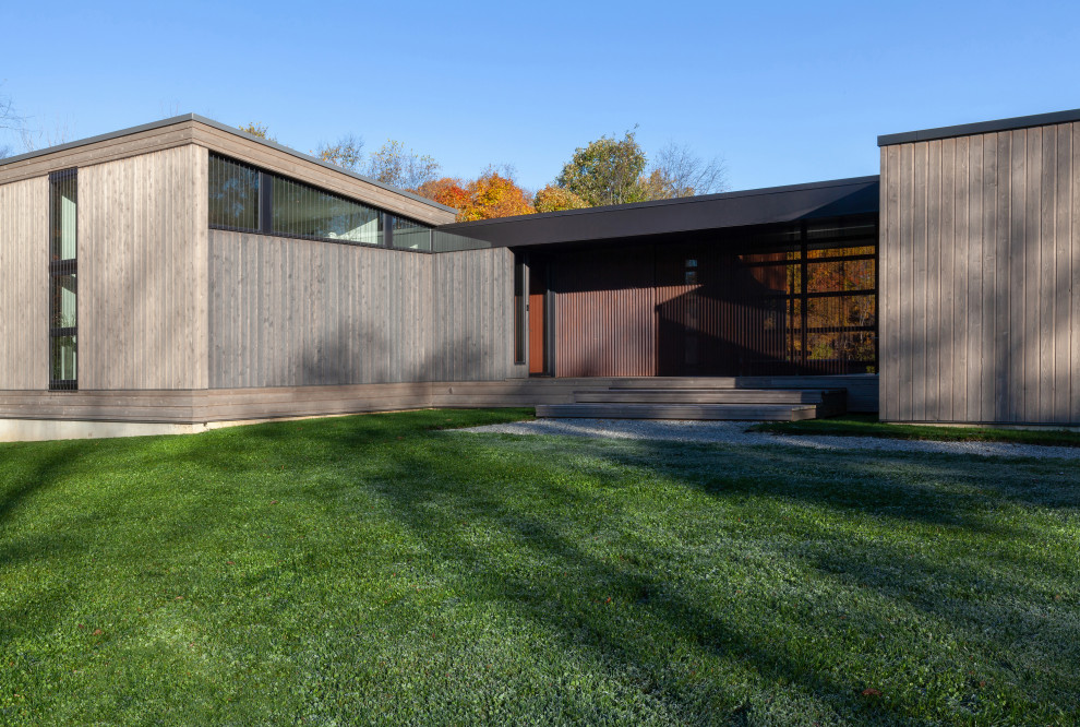 Cette image montre une petite façade de maison grise minimaliste en bois et bardage à clin de plain-pied avec un toit en appentis, un toit en métal et un toit gris.