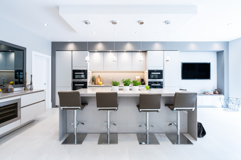 Inspiration for a large contemporary eat-in kitchen in Hampshire with flat-panel cabinets, grey cabinets, quartz benchtops, grey splashback, stone slab splashback, stainless steel appliances, with island and grey benchtop.