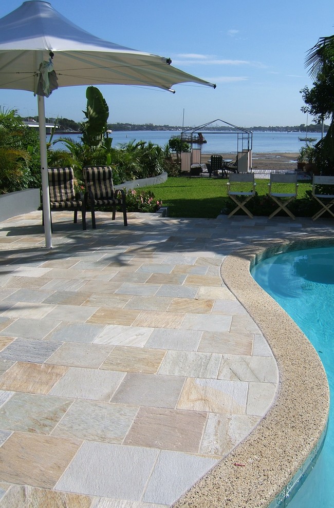 Mid-sized contemporary backyard kidney-shaped lap pool in Sydney with natural stone pavers.