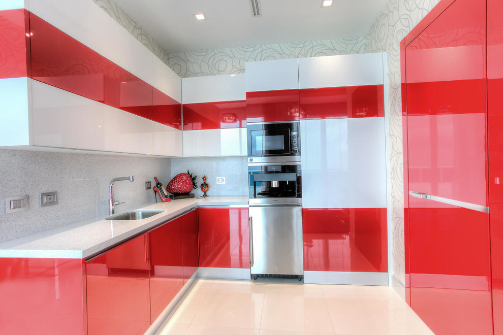 Photo of a small contemporary u-shaped open plan kitchen in Miami with an undermount sink, flat-panel cabinets, red cabinets, quartz benchtops, grey splashback, stone slab splashback, coloured appliances, porcelain floors and no island.