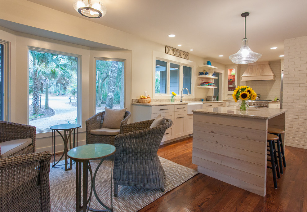 Photo of a beach style u-shaped open plan kitchen in Charleston with a farmhouse sink, shaker cabinets, white cabinets, granite benchtops, stainless steel appliances, medium hardwood floors and with island.