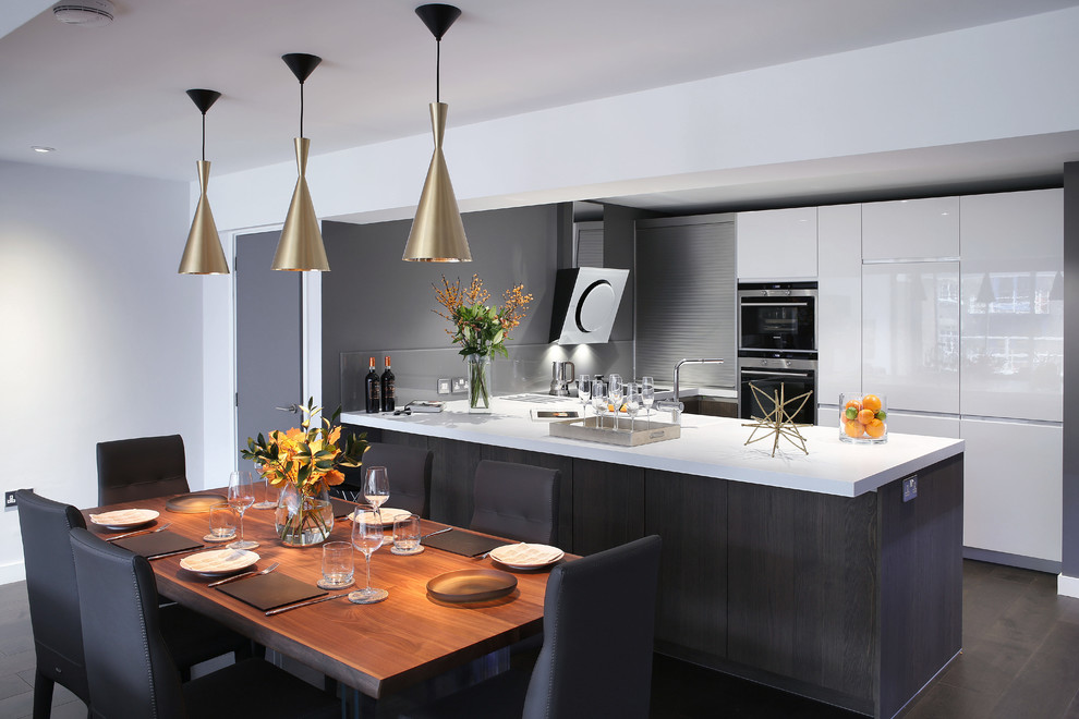 This is an example of a contemporary u-shaped open plan kitchen in London with flat-panel cabinets, white cabinets, grey splashback, stainless steel appliances and a peninsula.