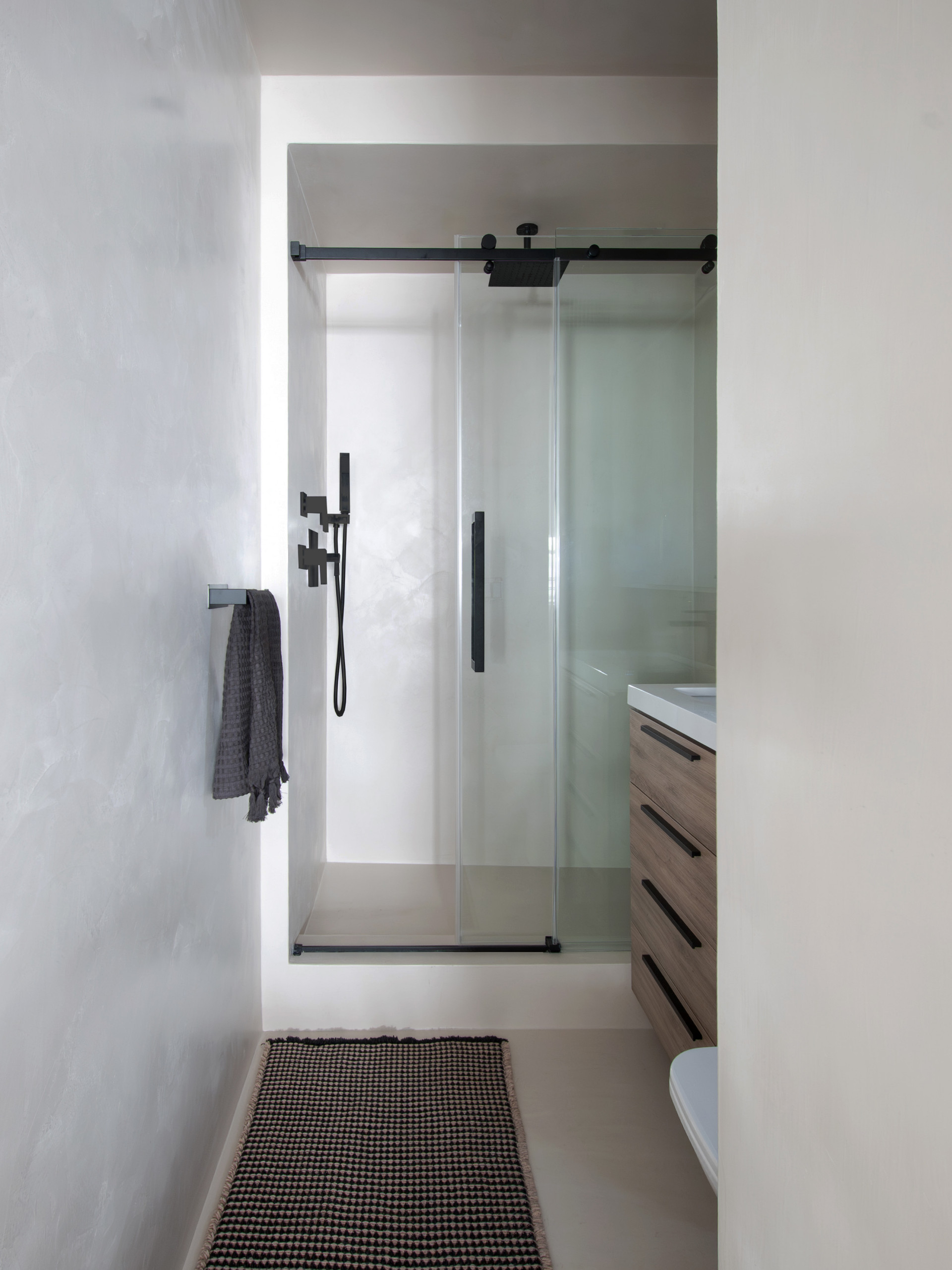 A sleek, modern bathroom renovation in New York City featuring a seamless microcement finish for a clean, grout-free look. This contemporary NYC bathroom design combines minimalist lines, a custom woo