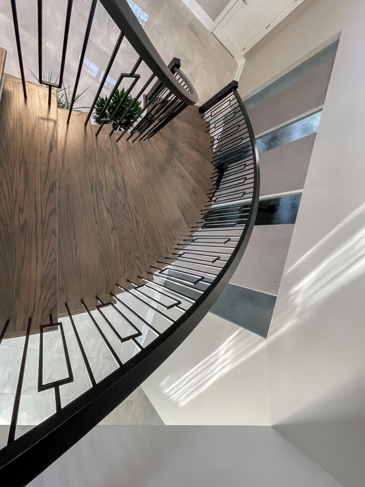 Идея дизайна: огромная изогнутая лестница в стиле неоклассика (современная классика) с деревянными ступенями, крашенными деревянными подступенками, перилами из смешанных материалов и обоями на стенах