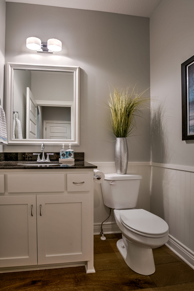Design ideas for a transitional powder room in Kansas City with shaker cabinets, white cabinets, granite benchtops, grey walls, medium hardwood floors and an undermount sink.