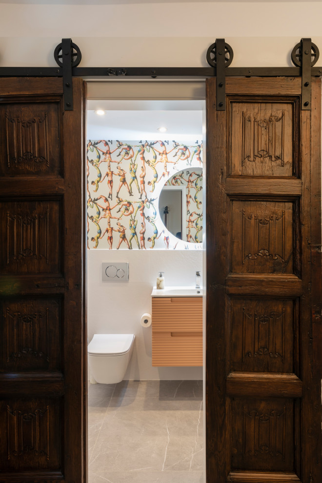 Пример оригинального дизайна: маленький туалет в современном стиле с фасадами с выступающей филенкой, оранжевыми фасадами, инсталляцией, белой плиткой, керамической плиткой, белыми стенами, полом из керамической плитки, накладной раковиной, столешницей из искусственного камня, серым полом, белой столешницей, подвесной тумбой и обоями на стенах для на участке и в саду