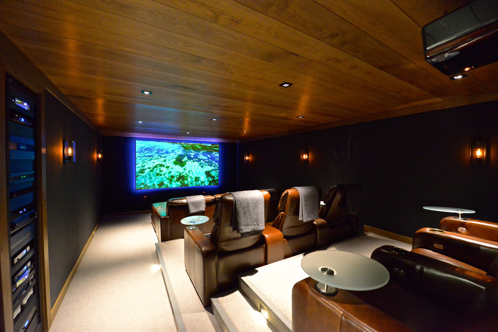 This is an example of a mid-sized modern enclosed home theatre in Other with black walls, carpet, a projector screen and beige floor.