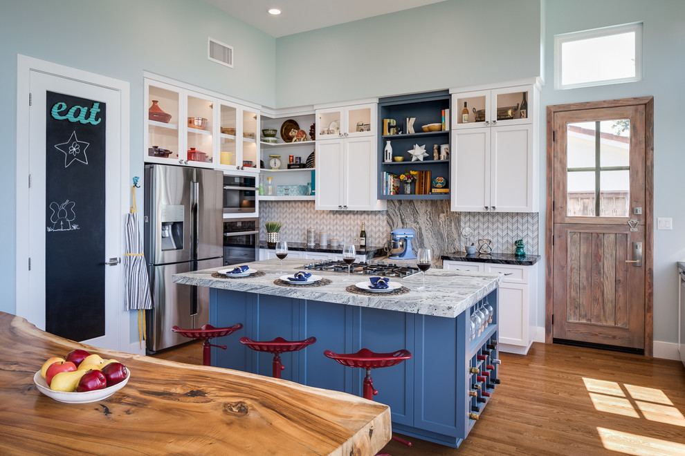 Mid-sized transitional l-shaped eat-in kitchen in San Diego with a farmhouse sink, shaker cabinets, white cabinets, granite benchtops, multi-coloured splashback, mosaic tile splashback, stainless steel appliances, medium hardwood floors and with island.