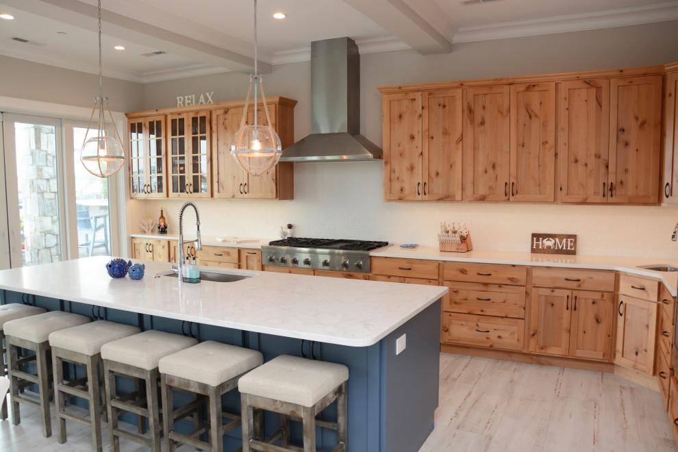 Photo of a large beach style single-wall open plan kitchen in DC Metro with an undermount sink, shaker cabinets, light wood cabinets, quartz benchtops, white splashback, stainless steel appliances, with island, white floor, white benchtop and coffered.