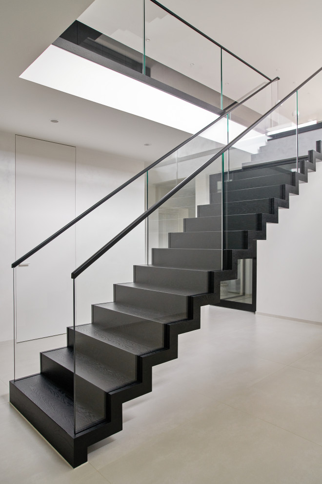 Réalisation d'un escalier flottant design de taille moyenne avec des marches en bois, des contremarches en bois et un garde-corps en verre.