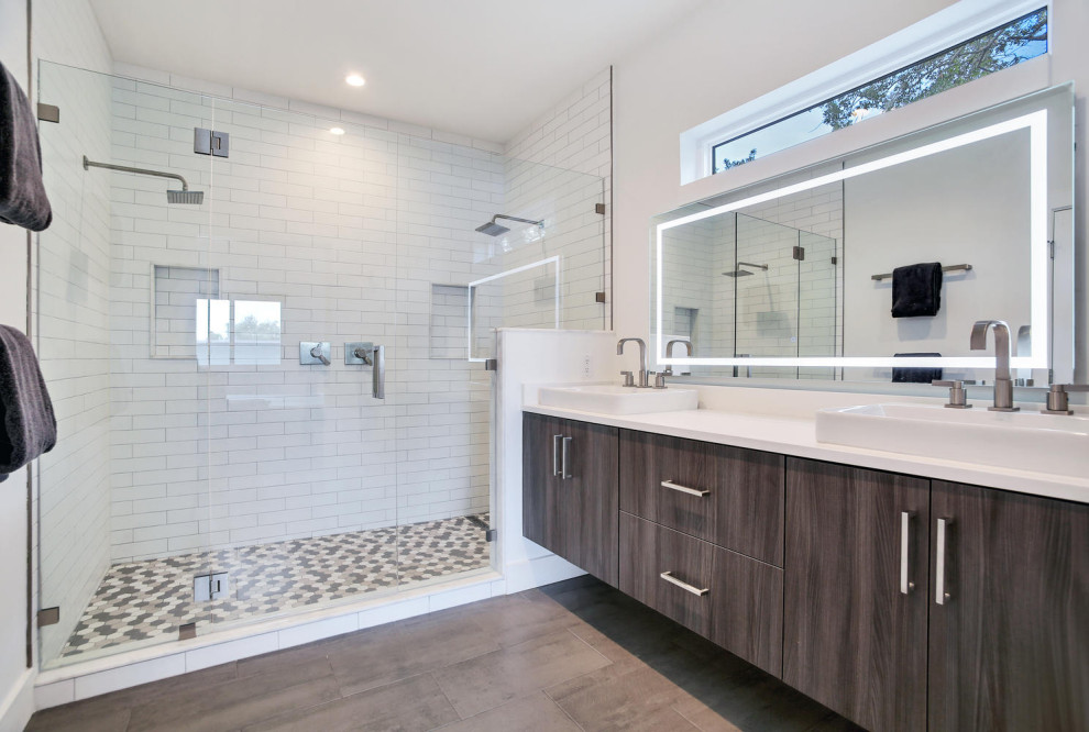 Inspiration for a large industrial master bathroom in Tampa with flat-panel cabinets, brown cabinets, a two-piece toilet, white tile, ceramic tile, white walls, laminate floors, a trough sink, engineered quartz benchtops, grey floor, a hinged shower door and white benchtops.