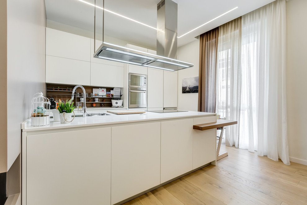 Inspiration for a mid-sized modern galley open plan kitchen in Rome with flat-panel cabinets, white cabinets, quartz benchtops, brown splashback, stainless steel appliances, light hardwood floors, a peninsula and beige floor.