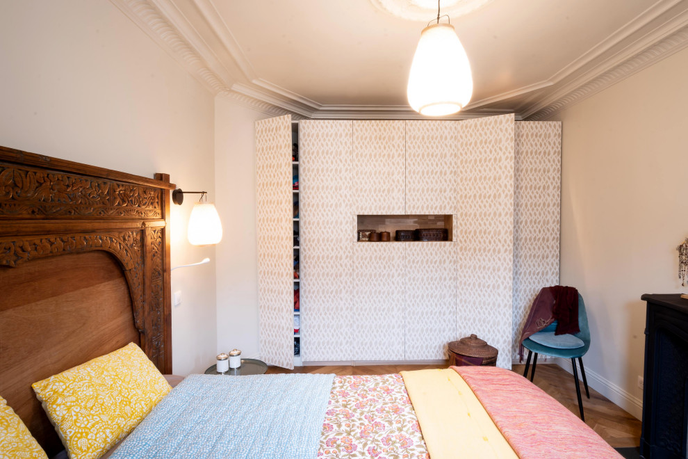 Immagine di una camera matrimoniale tropicale di medie dimensioni con pareti bianche, parquet chiaro, camino classico e pavimento beige