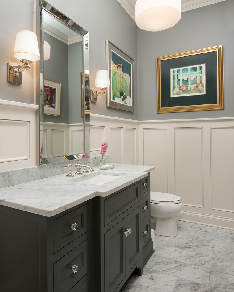 This is an example of a mid-sized traditional powder room in Minneapolis with recessed-panel cabinets, grey cabinets, grey walls, marble floors, an undermount sink, marble benchtops, grey floor and grey benchtops.