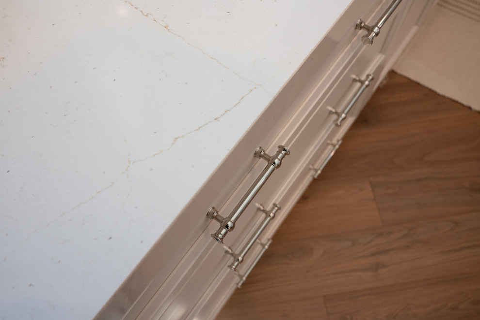 Inspiration for a large transitional l-shaped vinyl floor and brown floor open concept kitchen remodel in San Diego with an undermount sink, shaker cabinets, white cabinets, quartz countertops, beige backsplash, porcelain backsplash, stainless steel appliances, an island and white countertops