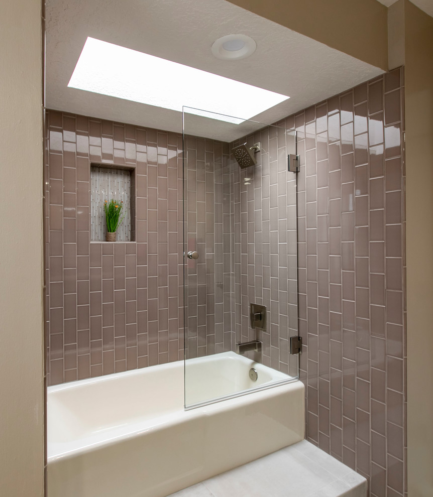 Mid-sized modern 3/4 bathroom in Albuquerque with flat-panel cabinets, dark wood cabinets, a drop-in tub, a shower/bathtub combo, a one-piece toilet, pink tile, subway tile, beige walls, porcelain floors, an undermount sink, quartzite benchtops, beige floor, a hinged shower door and beige benchtops.