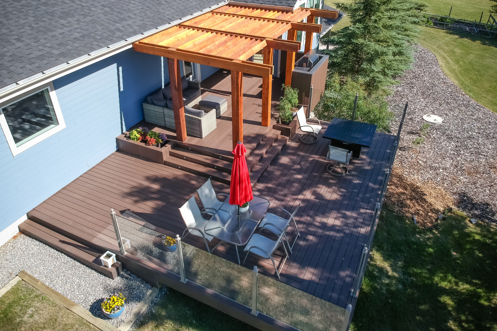 Example of a mid-sized trendy backyard deck design in Calgary with a pergola
