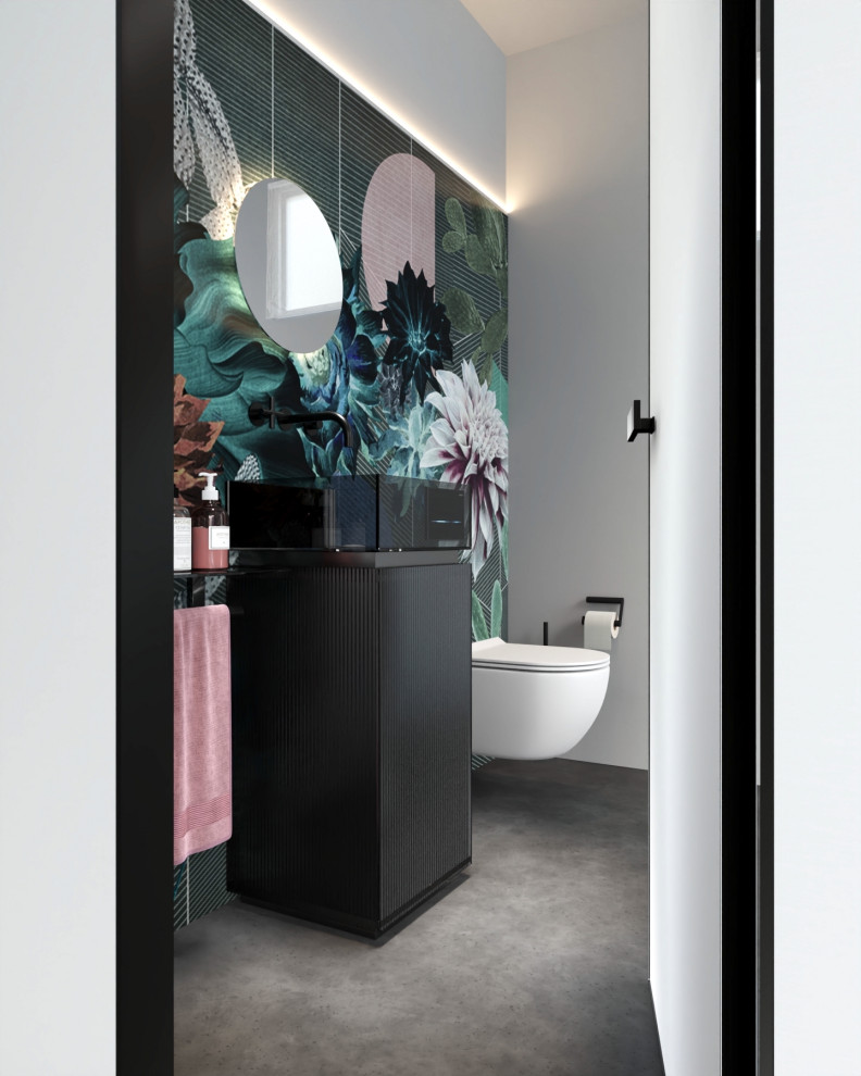 Modern inredning av ett litet svart svart badrum, med luckor med glaspanel, svarta skåp, en vägghängd toalettstol, flerfärgade väggar, ett piedestal handfat och bänkskiva i glas
