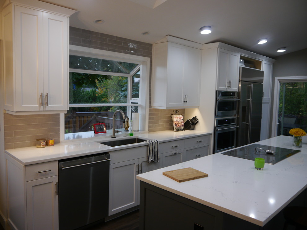 Inspiration for a large transitional dark wood floor and brown floor eat-in kitchen remodel in Seattle with a single-bowl sink, shaker cabinets, white cabinets, solid surface countertops, beige backsplash, ceramic backsplash, stainless steel appliances, an island and white countertops