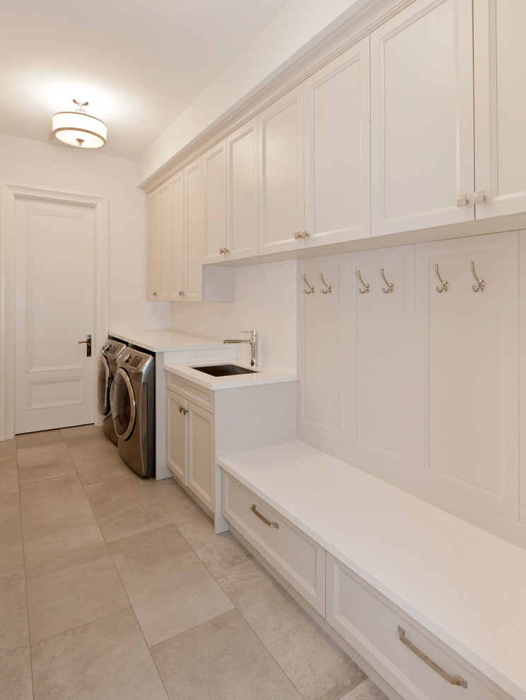 Mid-sized contemporary single-wall utility room in Los Angeles with an undermount sink, shaker cabinets, white cabinets, quartz benchtops, white walls, limestone floors and a side-by-side washer and dryer.