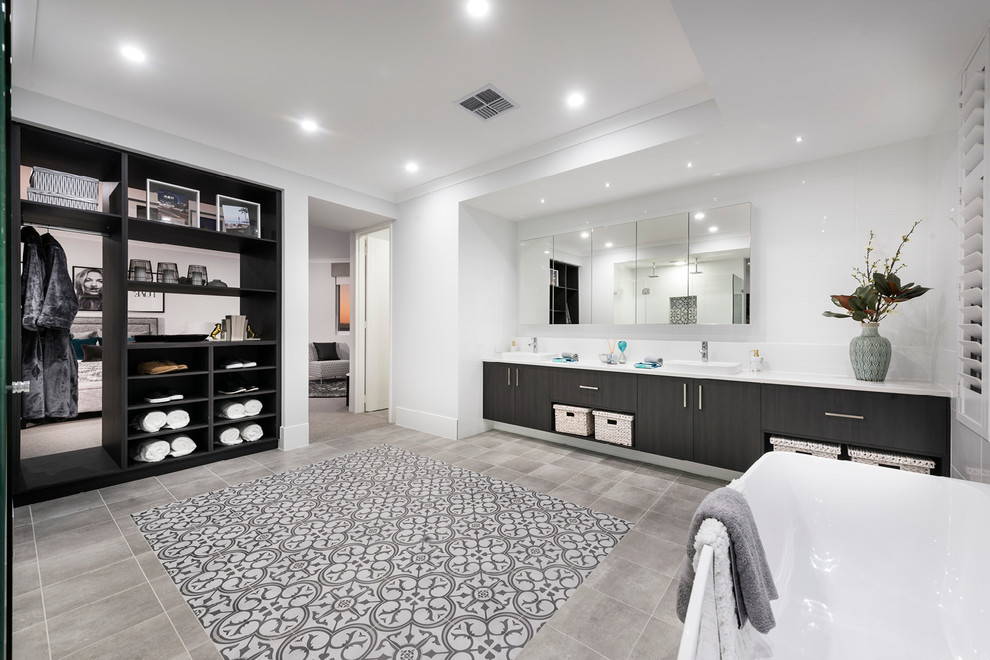 This is an example of an expansive contemporary master bathroom in Perth with flat-panel cabinets, light wood cabinets, a drop-in tub, a corner shower, a one-piece toilet, gray tile, porcelain tile, white walls, porcelain floors, a drop-in sink, engineered quartz benchtops, grey floor and a hinged shower door.