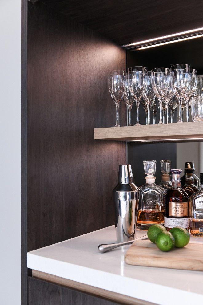 Design ideas for a small contemporary single-wall home bar in Sydney with no sink, dark wood cabinets, quartz benchtops, multi-coloured splashback, mirror splashback, ceramic floors and white benchtop.