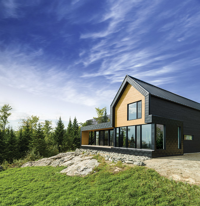 Photo of a large contemporary two-storey black exterior in Montreal with wood siding.