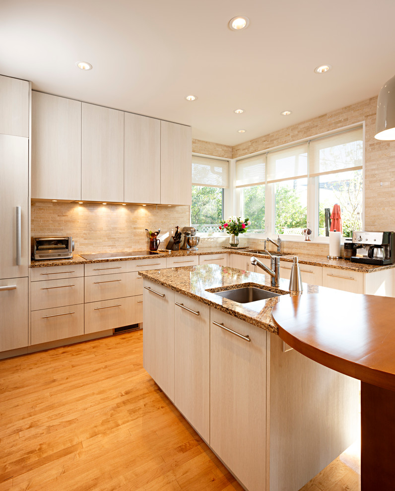Eat-in kitchen - mid-sized transitional l-shaped medium tone wood floor and brown floor eat-in kitchen idea in Ottawa with a single-bowl sink, flat-panel cabinets, beige cabinets, granite countertops, beige backsplash, stone tile backsplash, stainless steel appliances and an island