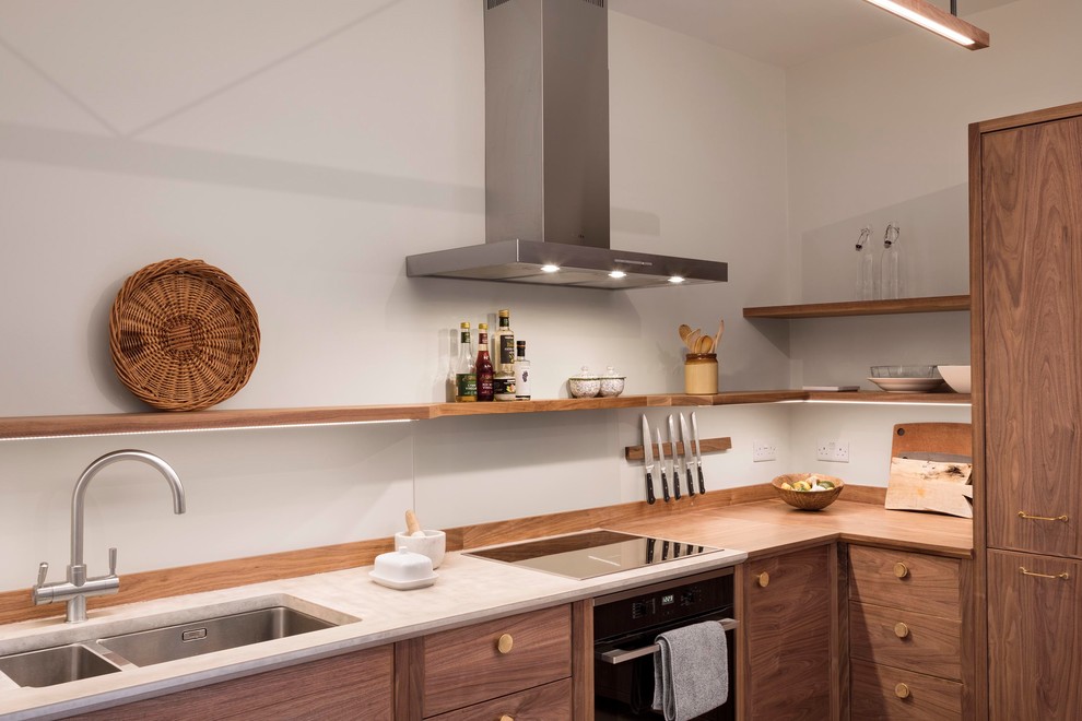 Photo of a mid-sized modern l-shaped eat-in kitchen in London with a drop-in sink, flat-panel cabinets, dark wood cabinets, concrete benchtops, grey splashback, glass sheet splashback, stainless steel appliances, light hardwood floors, no island, beige floor and grey benchtop.