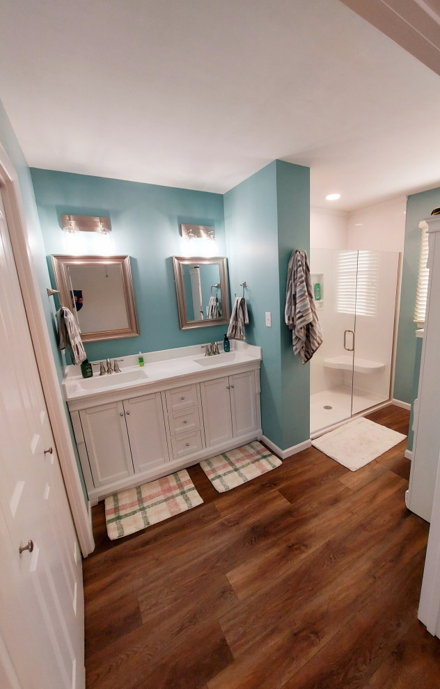 Стильный дизайн: большая главная ванная комната в стиле модернизм с белыми фасадами, душем без бортиков, унитазом-моноблоком, белой плиткой, плиткой из сланца, синими стенами, полом из ламината, накладной раковиной, столешницей из искусственного кварца, коричневым полом, душем с распашными дверями, белой столешницей, сиденьем для душа, тумбой под две раковины и встроенной тумбой - последний тренд