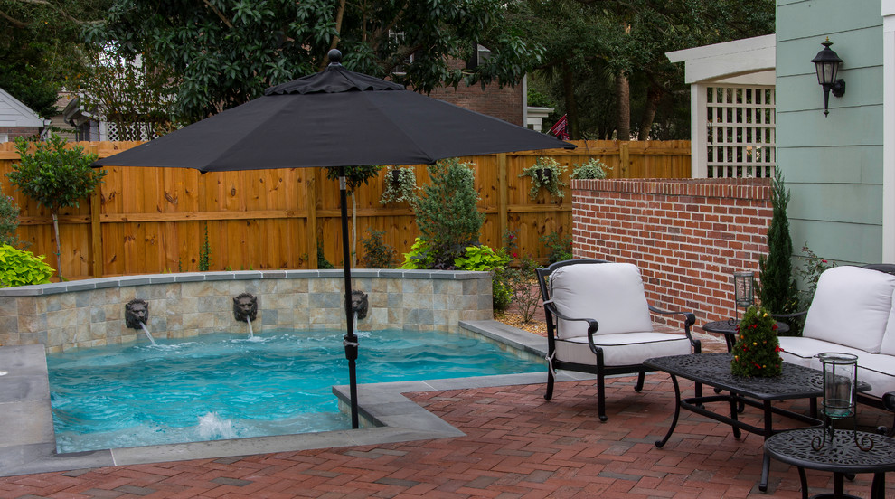 Photo of a small traditional backyard custom-shaped natural pool in Tampa with a hot tub and brick pavers.