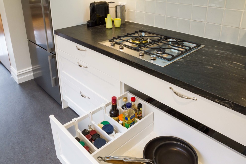 This is an example of a mid-sized transitional galley separate kitchen in Melbourne with a drop-in sink, shaker cabinets, white cabinets, granite benchtops and no island.