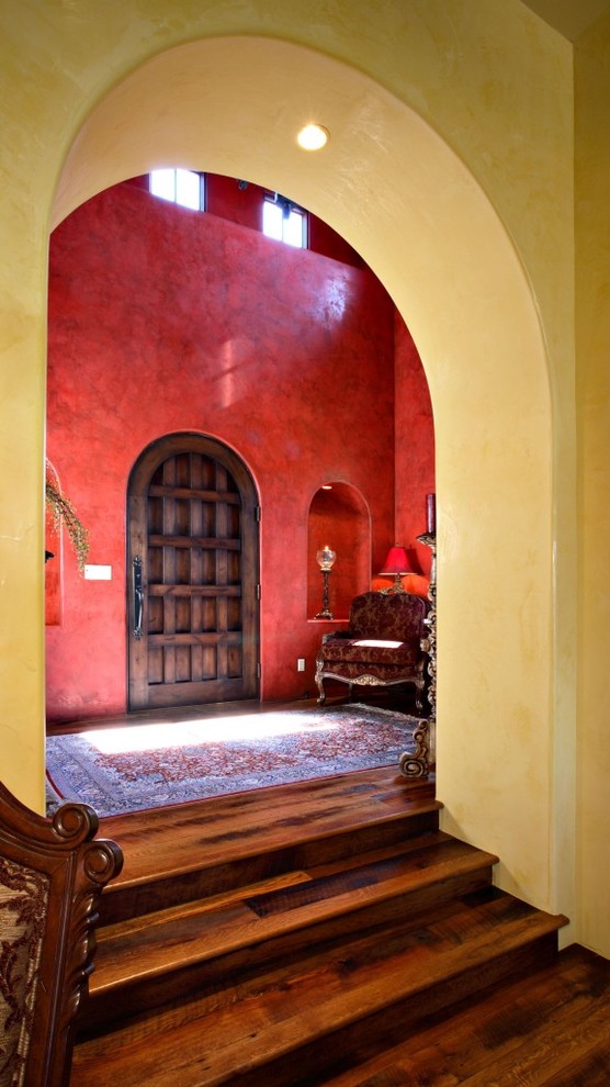 Inspiration for an expansive mediterranean foyer in Phoenix with red walls, dark hardwood floors and a single front door.