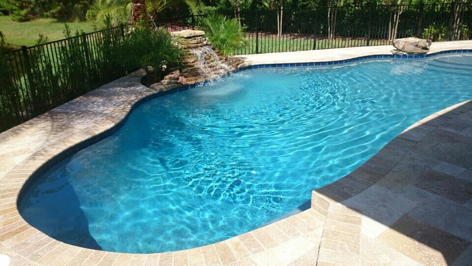 This is an example of a mid-sized contemporary backyard custom-shaped natural pool in Jacksonville with a water feature and natural stone pavers.