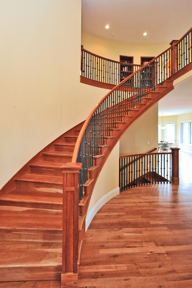 Photo of a large country wood curved staircase in Denver with wood risers and wood railing.