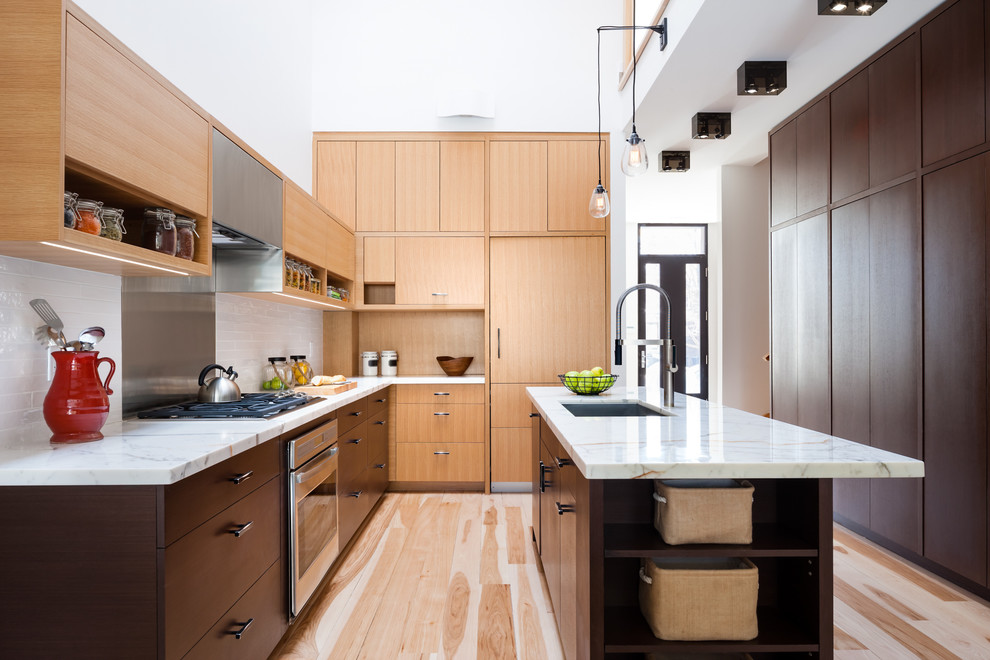 Design ideas for a contemporary l-shaped kitchen in Toronto with an undermount sink, flat-panel cabinets, light wood cabinets, white splashback, subway tile splashback, stainless steel appliances, medium hardwood floors and with island.