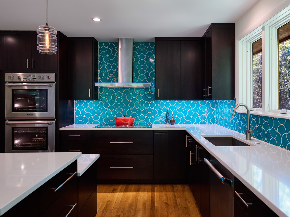 Inspiration for a large transitional l-shaped eat-in kitchen in Baltimore with an undermount sink, flat-panel cabinets, medium wood cabinets, granite benchtops, blue splashback, cement tile splashback, stainless steel appliances, medium hardwood floors, multiple islands and brown floor.