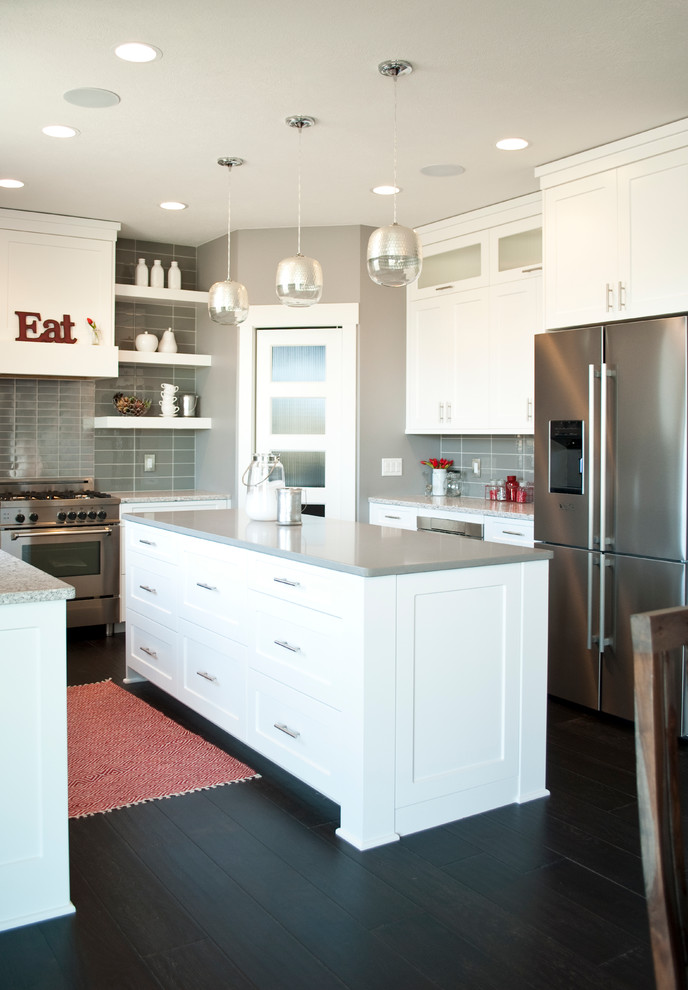 Inspiration for a transitional u-shaped kitchen remodel with an undermount sink, recessed-panel cabinets, white cabinets, quartz countertops, gray backsplash, stainless steel appliances and an island